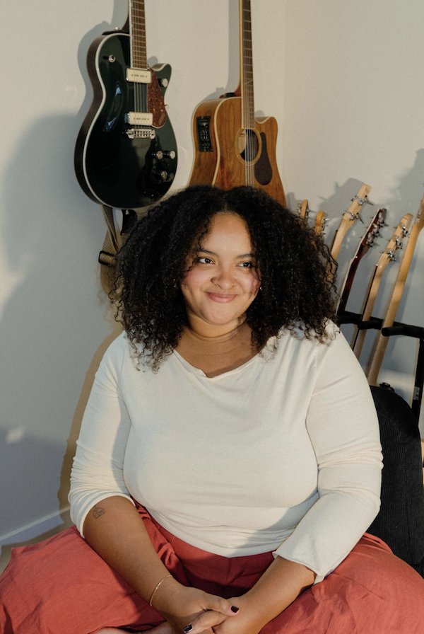 Adjenai sitting in front of guitars