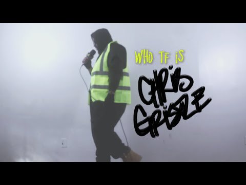 Chris Gristle performing in a hi-vis vest and fog, from his Who TF is Chris Gristle video.